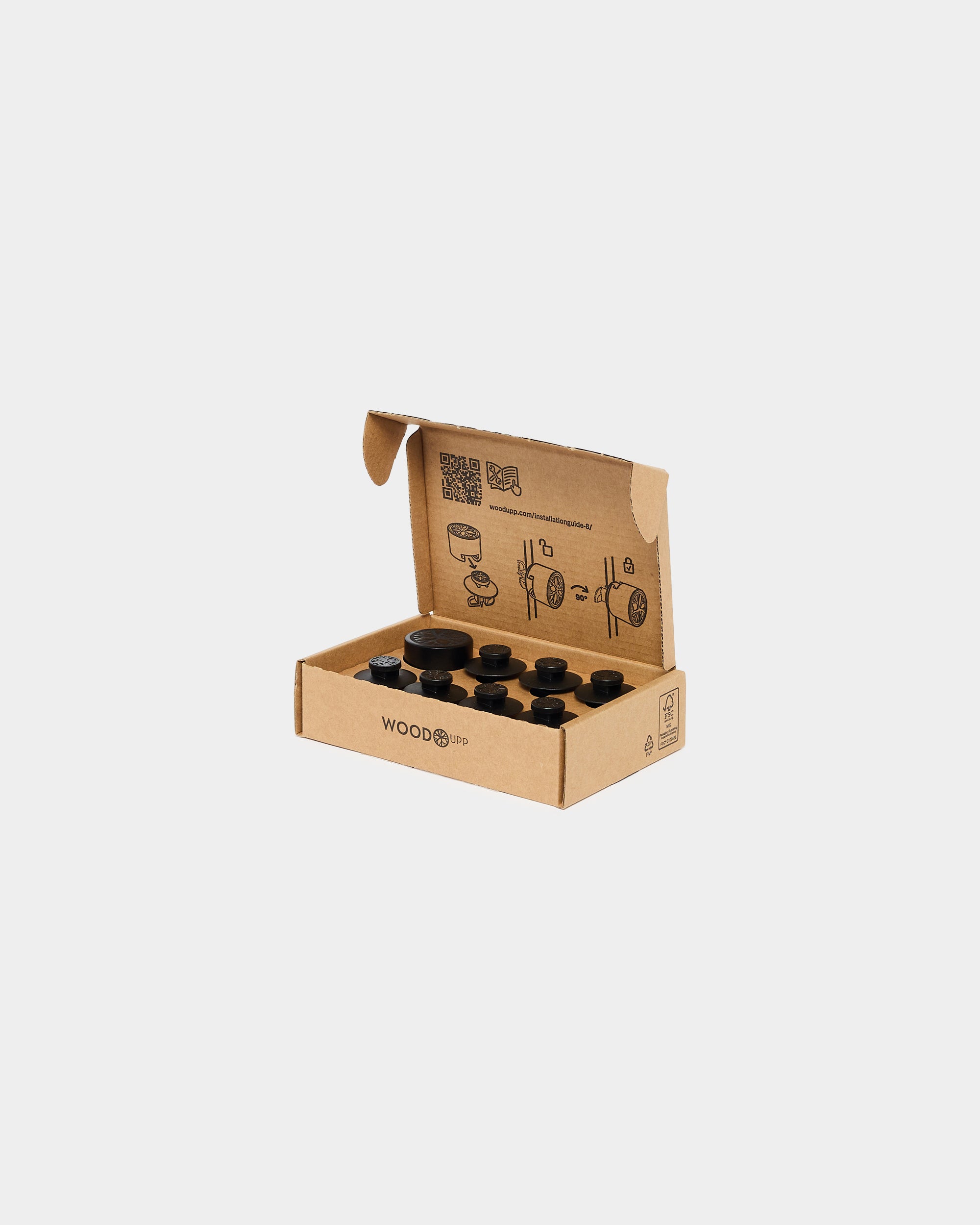 Open cardboard box containing dark wood acoustic panel pieces and printed assembly instructions inside the lid, suitable for assembling Nordic wall panels.